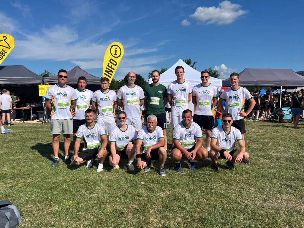 Gruppenfoto des orbau-Teams in weißen Laufshirts vor den Zelten beim Firmenlauf.