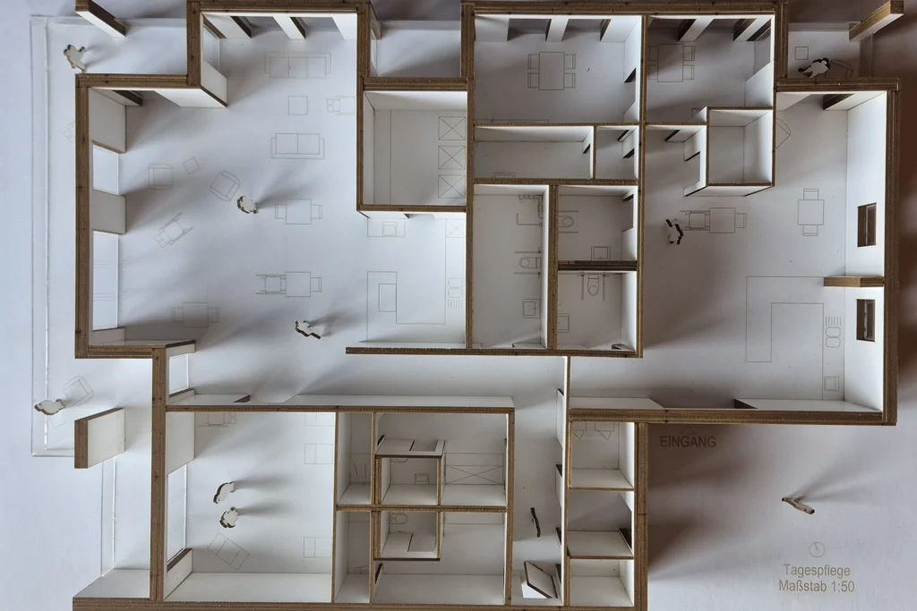 Top-Down-Ansicht eines Architekturmodells mit mehreren Aufenthalts- und Ruheräumen, die die geplante Tagespflege innerhalb einer Seniorenwohnanlage darstellen.