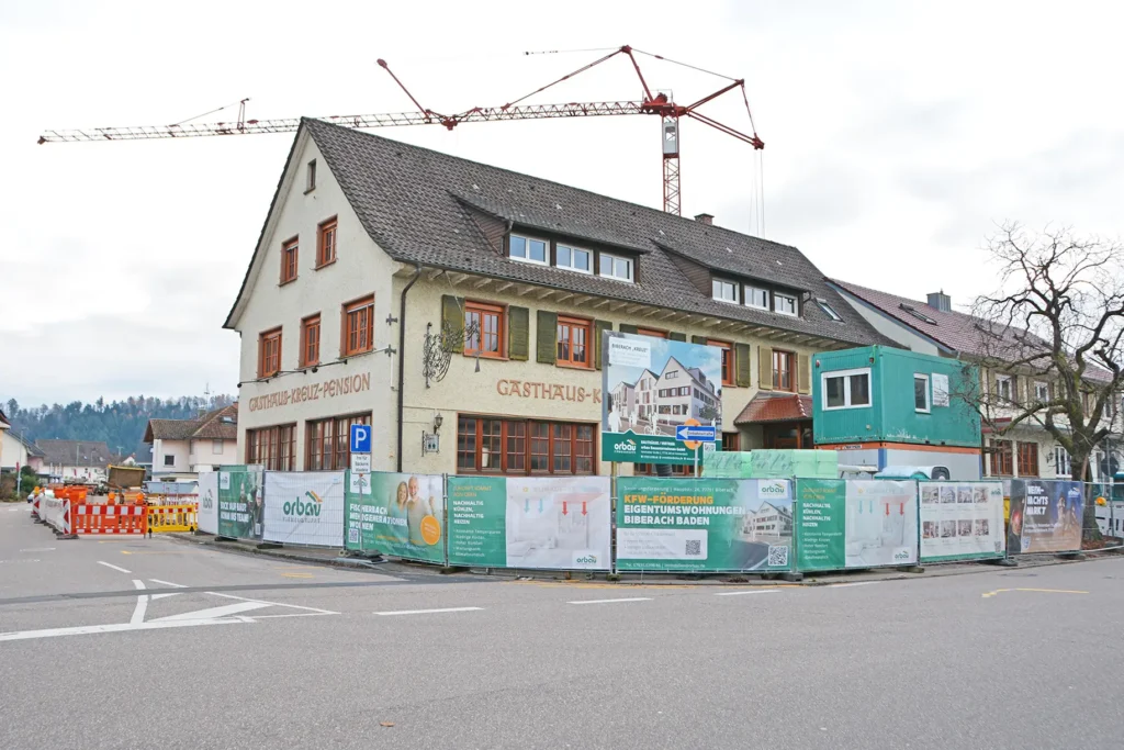 Das Gebäude des ehemaligen Gasthaus Kreuz in Biberach mit Bauzäunen umringt und Baukran im Hintergrund.