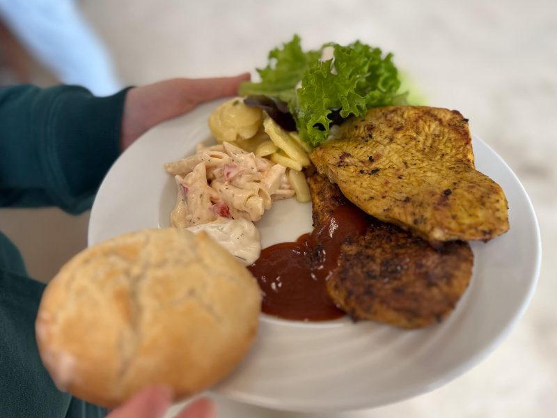 Gefüllter Teller mit Grillgut, Salaten und Brötchen beim Sommerfest der orbau Gruppe.