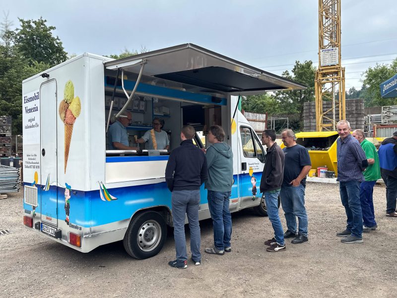 Mitarbeitende stehen beim Sommerfest 2025 am Eismobil vom Eiscafé Venezia auf dem orbau Bauhof in Gengenbach an.