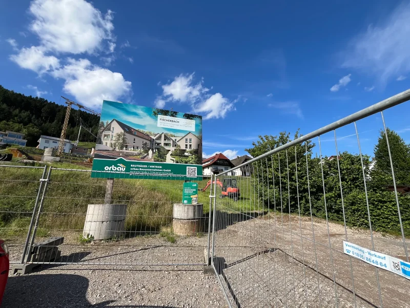 auschild des Projekts „Seniorenwohnen Fischerbach“ mit Visualisierung der geplanten Wohnanlage und orbau-Bagger im Hintergrund