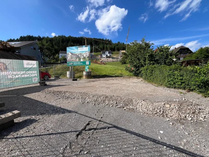 Banner mit Hinweis auf „Seniorenwohnen Fischerbach“ an der Hauptstraße, rotes Auto auf dem Grundstück, umliegende Wohnhäuser