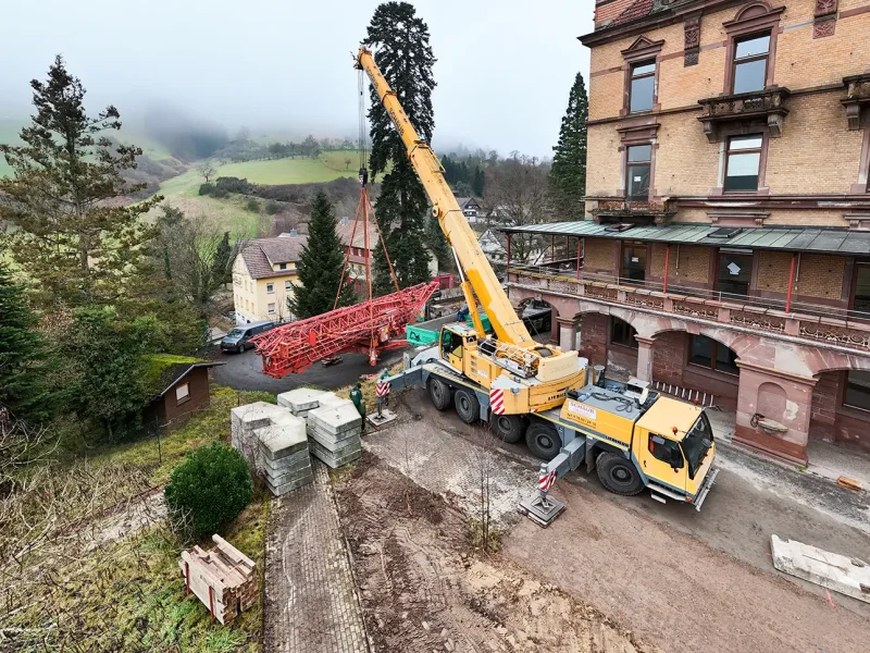 Gelber Mobilkran hebt Kranteile vor dem Schloss Rothschild, Mitarbeiter koordinieren den Aufbau