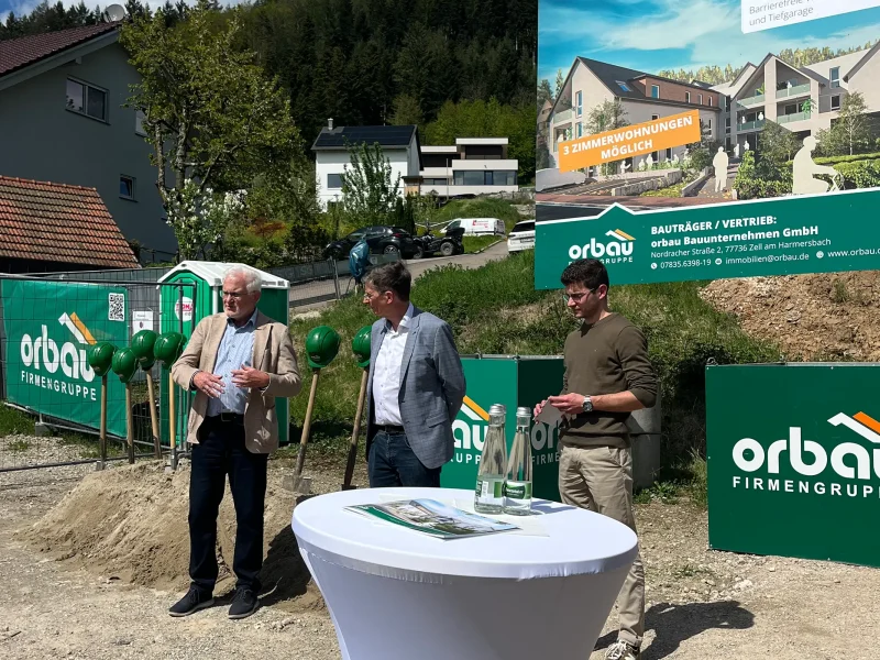 Projektvorstellung Mehrgenerationenwohnen Fischerbach mit Beteiligten vor großem Bauschild der orbau Firmengruppe