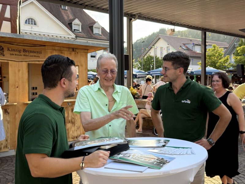 ORBAU-Geschäftsführer Luca Isenmann und Vertriebsmitarbeiter Julian Fieß im Gespräch mit einem Besucher beim Tavernenabend in Biberach.