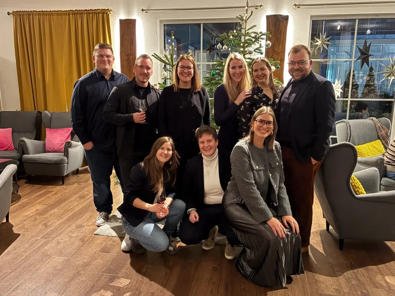 Mitarbeiterinnen und Mitarbeiter der orbau Firmengruppe lachend vor dem Weihnachtsbaum