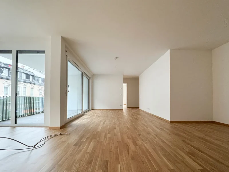 Blick von der Galerie mit Glasgeländer in das lichtdurchflutete Erdgeschoss einer Maisonettewohnung in Baden-Baden