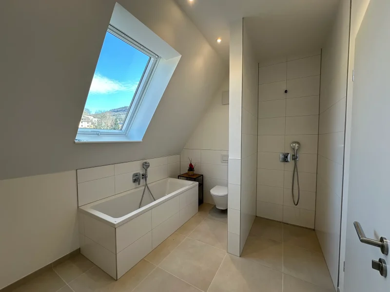Modernes Badezimmer mit Badewanne, bodengleicher Dusche und Dachfenster in einer Wohnung in Baden-Baden