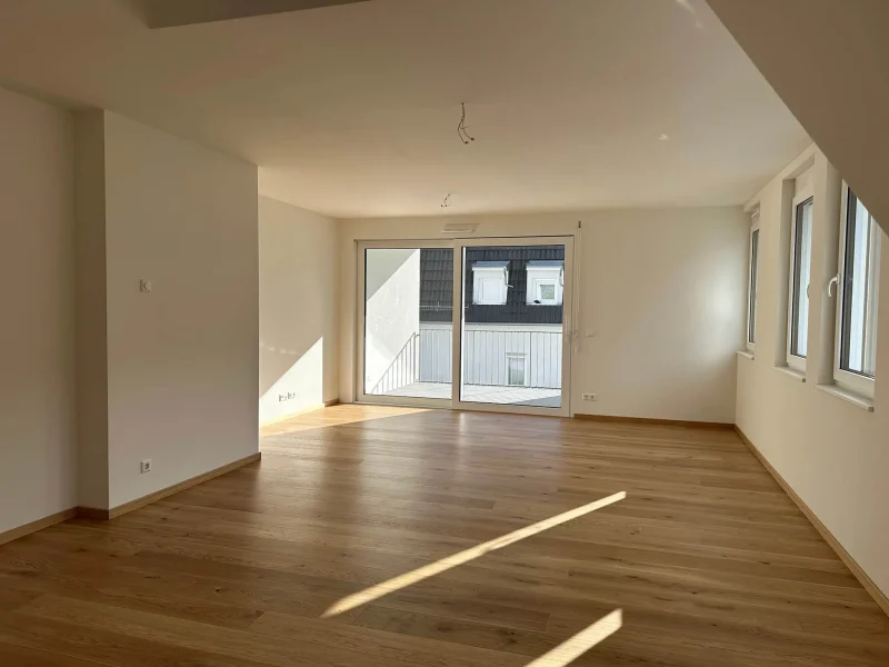 Heller Wohnbereich mit großen Fenstern und Zugang zum Balkon in einer modernen Wohnung in Baden-Baden