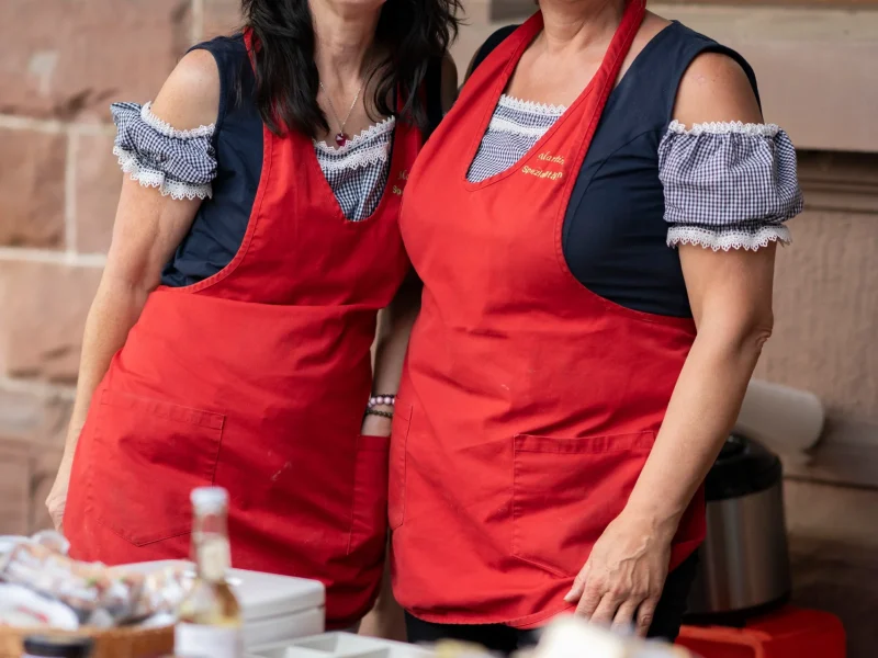 Zwei Frauen am Feinkost-Stand mit roter Schürze